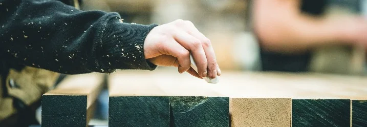 Person markiert Holz mit Kreide